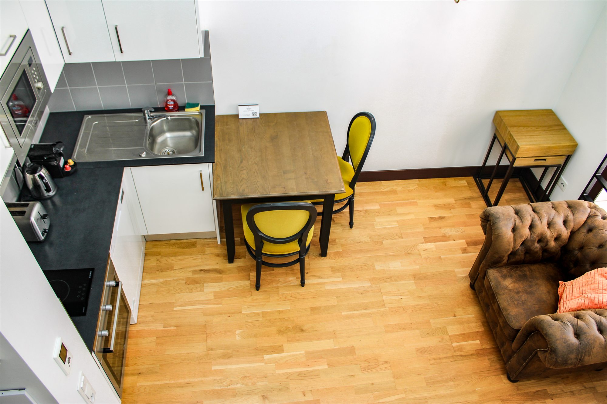 Séjour avec cuisine ouverte et canapé Chesterfield du duplex de la Résidence de l'Arsenal Royal