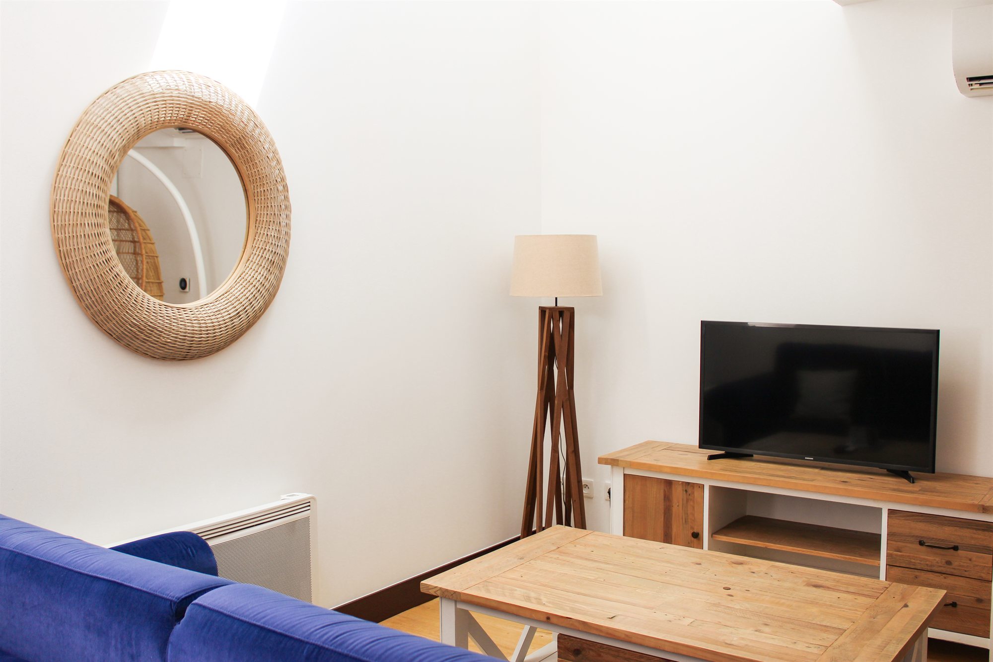 Appartement T2 — le salon avec miroir rond et télévision