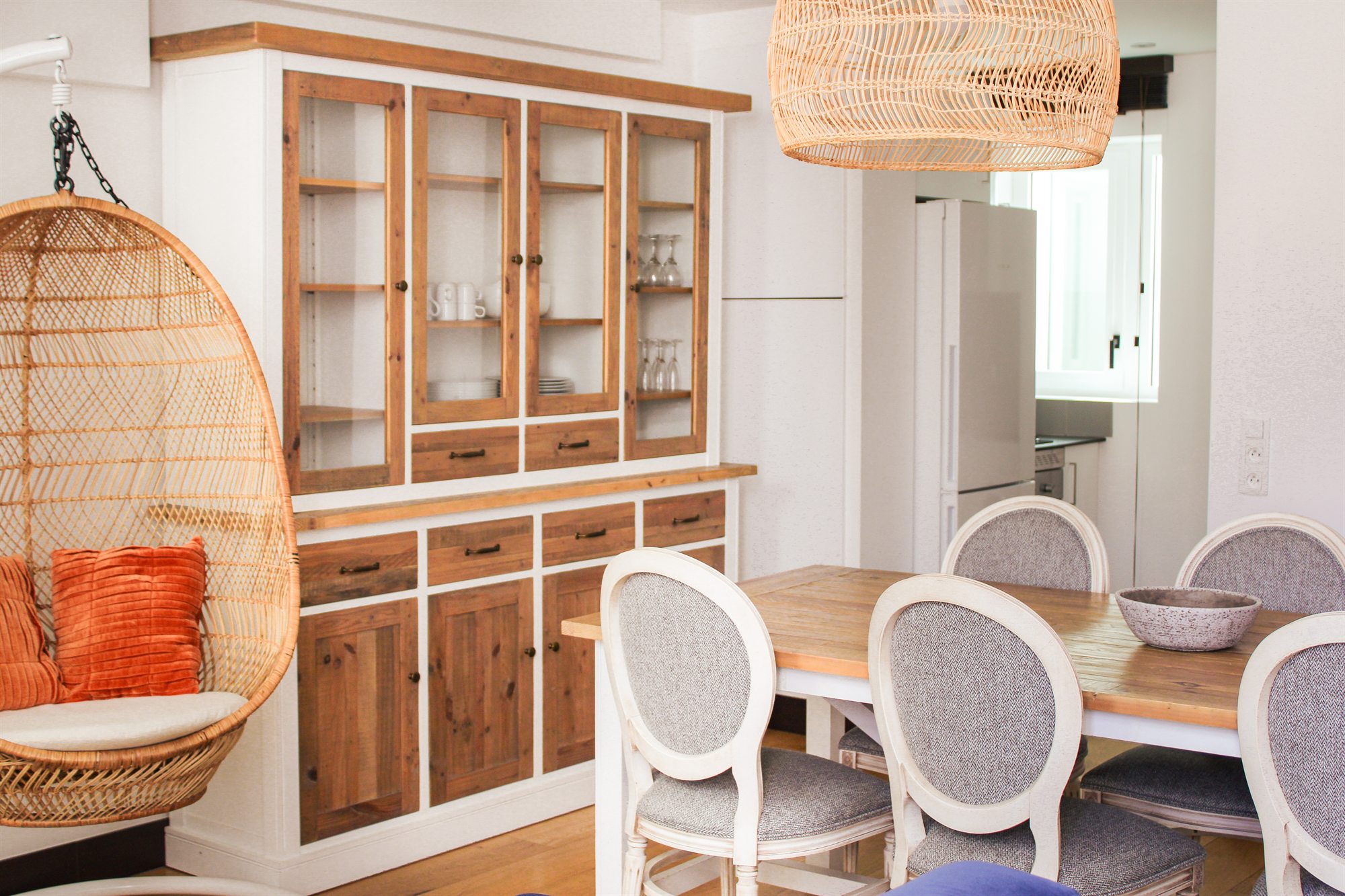 Appartement T2 — coin repas avec fauteuil suspendu et vaisselier